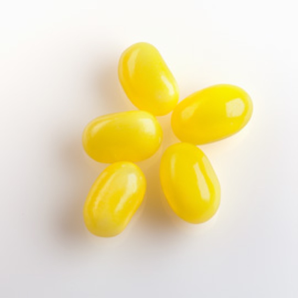 Five short, shiny, yellow-colored capsules positioned on a white surface.