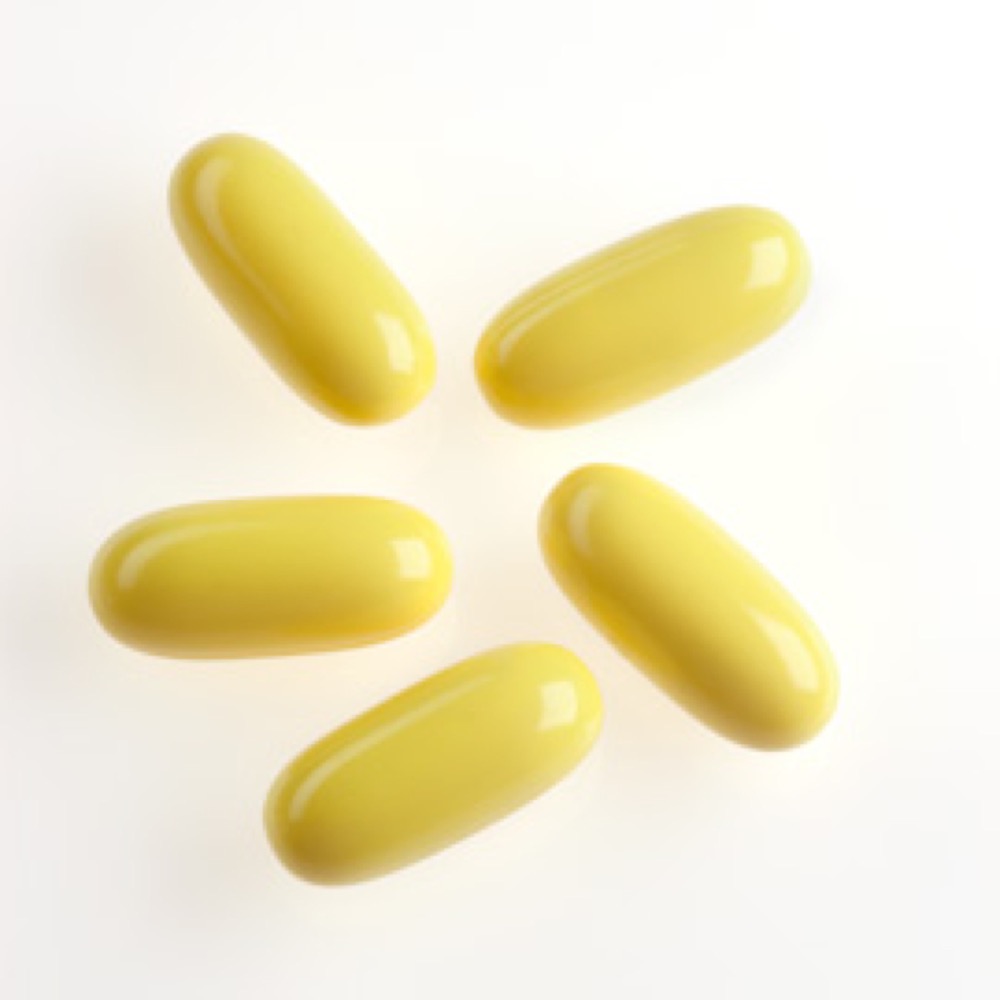 Five long, shiny, yellow-colored capsules positioned on a white surface.