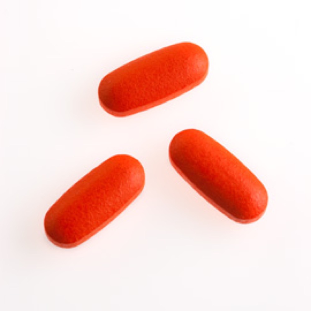 Three long, matte, red-colored capsules positioned on a white surface.
