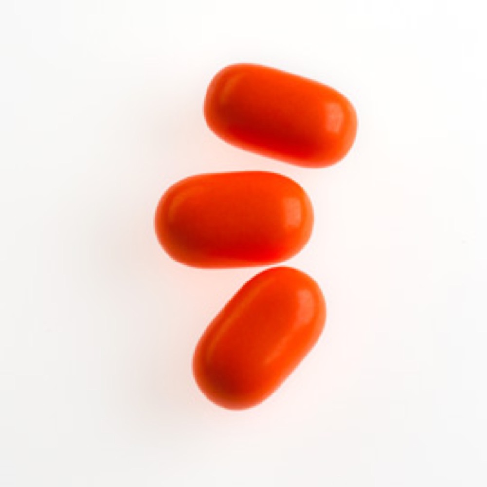 Three short, shiny, red-colored capsules positioned on a white surface.