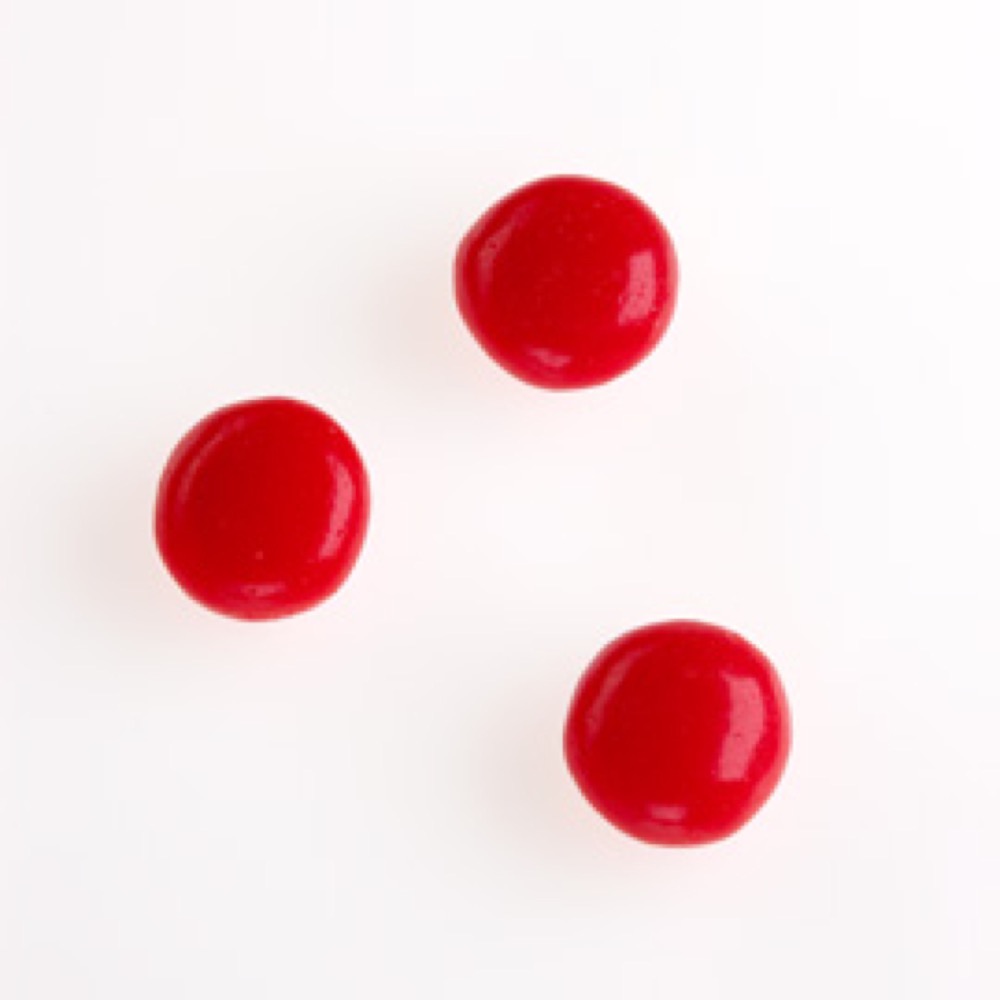 Three circular red pills that are shiny and vibrant in color against a white background.