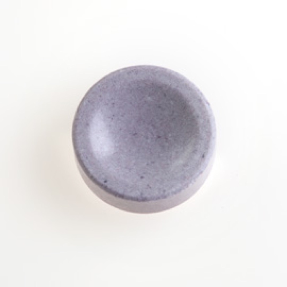 One circular, purple-colored lozenge, with a smooth surface.