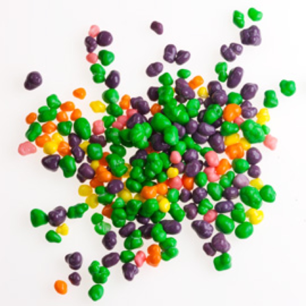 A pile of vibrant, multi-colored bead-like objects, arranged on a clean white surface.